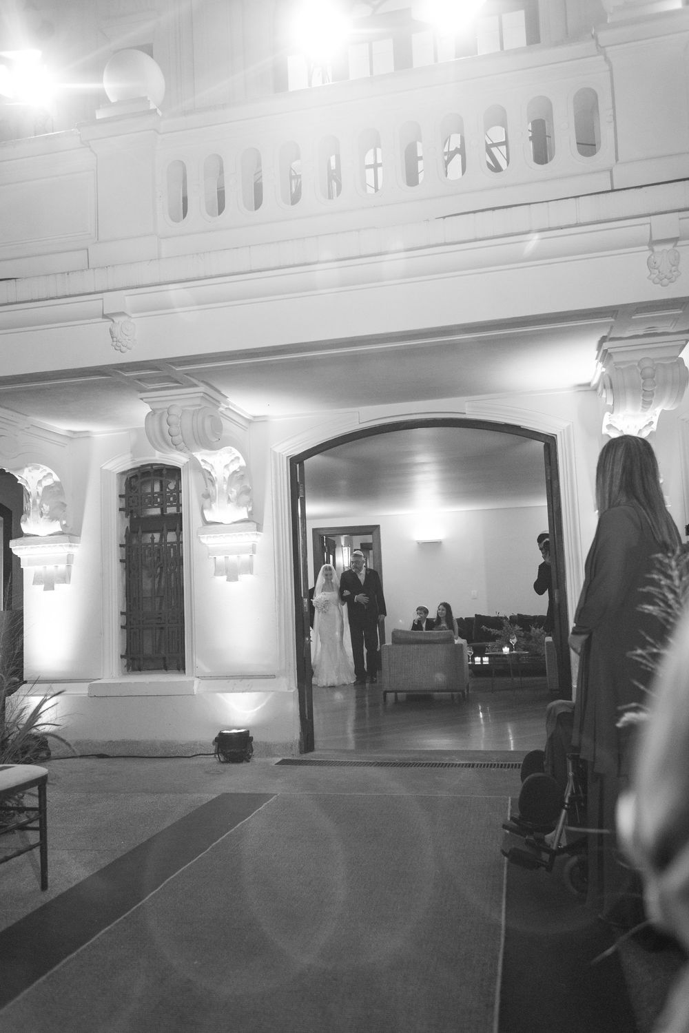 Black and white photograph of an empty interior space with architectural details and wall sconces.