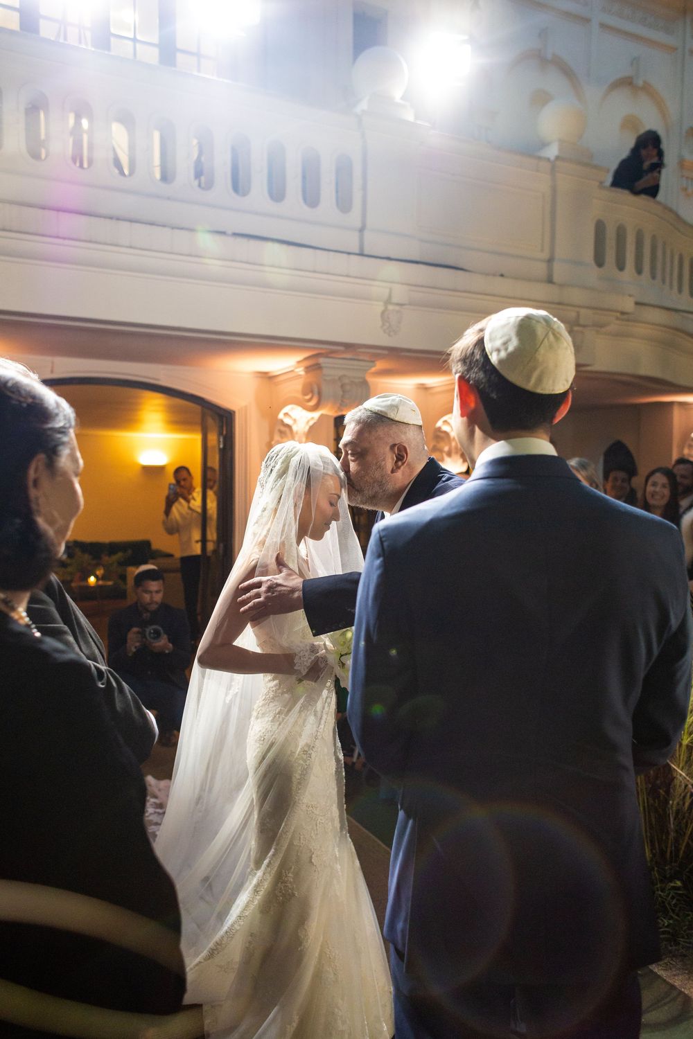 Wedding reception dance scene with bride in flowing white gown and guests in formal attire.