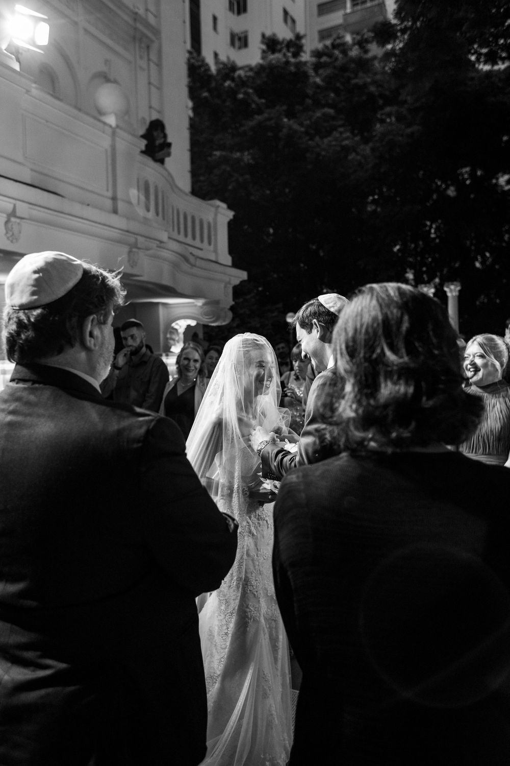 A black and white photo capturing a wedding ceremony from the perspective of guests.