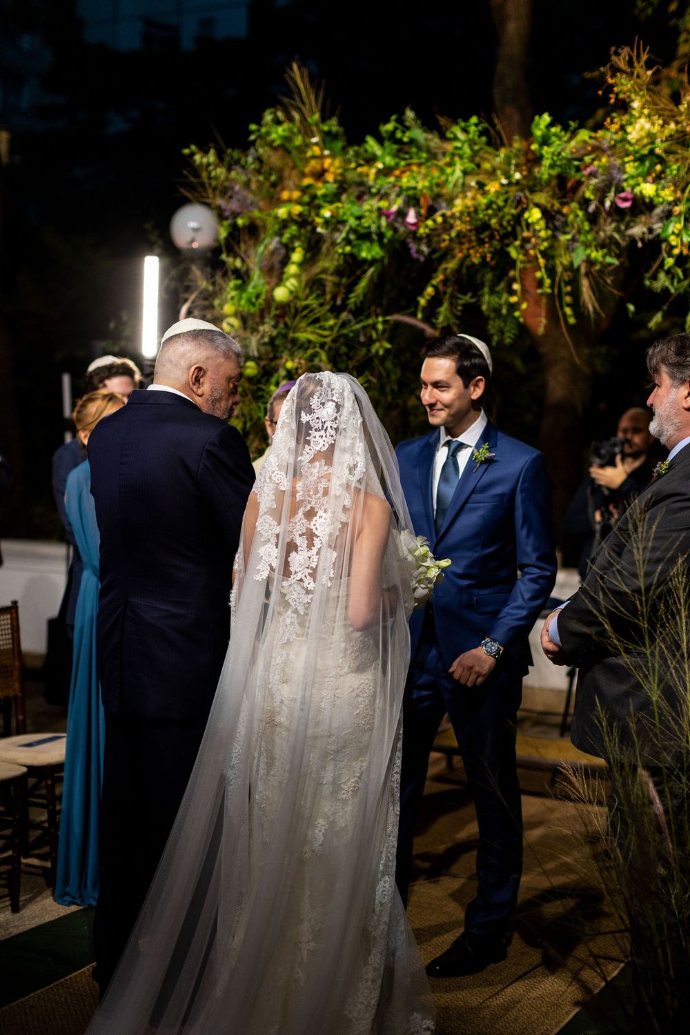 A wedding ceremony sequence shows a couple during their evening outdoor celebration with guests and floral decor.