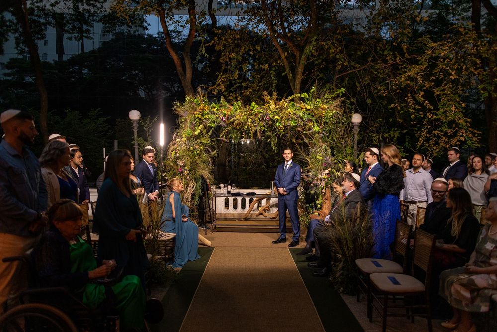 Outdoor evening wedding ceremony in a garden setting with warm lighting and natural decor.