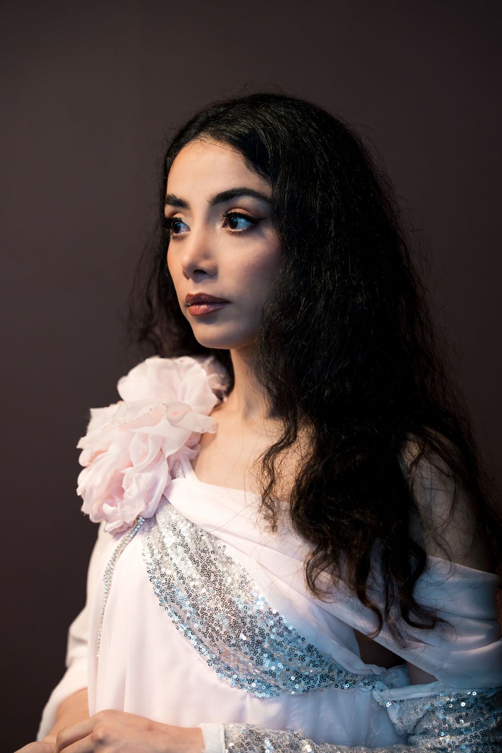 Artistic portrait series in white ruffled dress with glitter details and dramatic makeup against dark background.