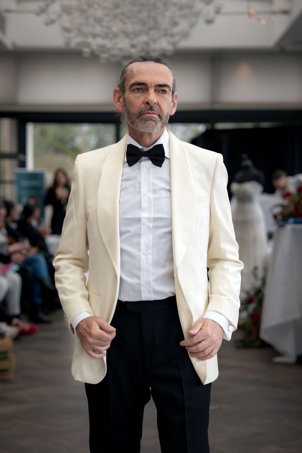 A person wearing a classic cream dinner jacket with black bow tie and white dress shirt in formal attire.