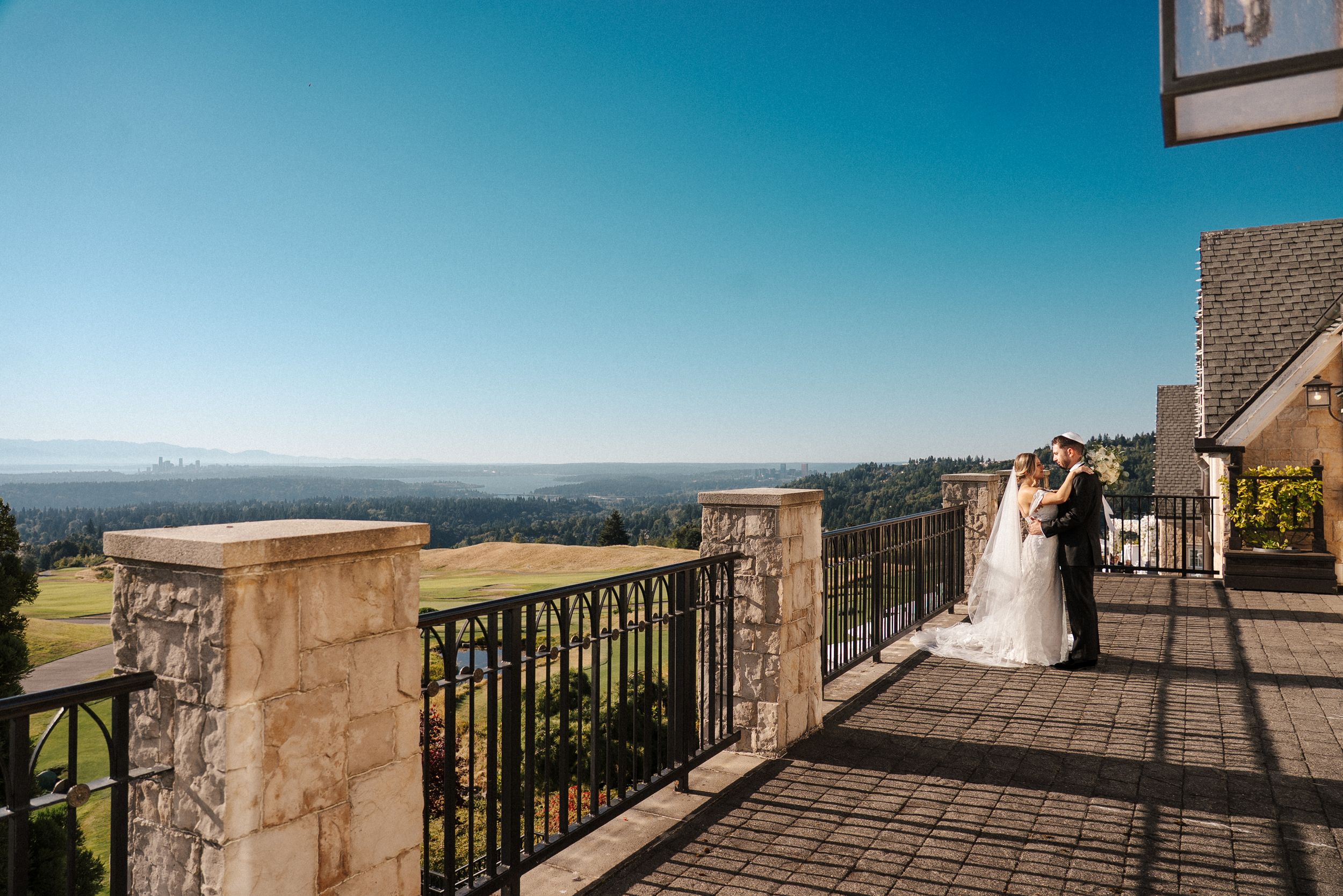 A panoramic view of a stone balcony overlooking a scenic coastal landscape with mountains and ocean in the distance.
