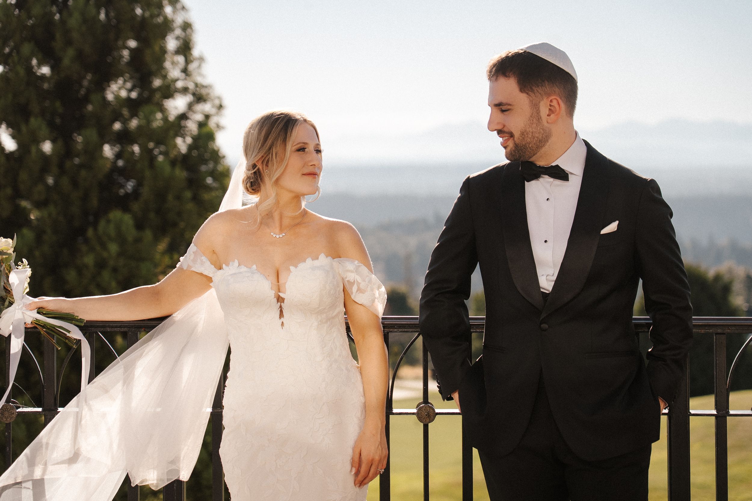 A romantic wedding couple poses together against a scenic mountain backdrop on their special day.