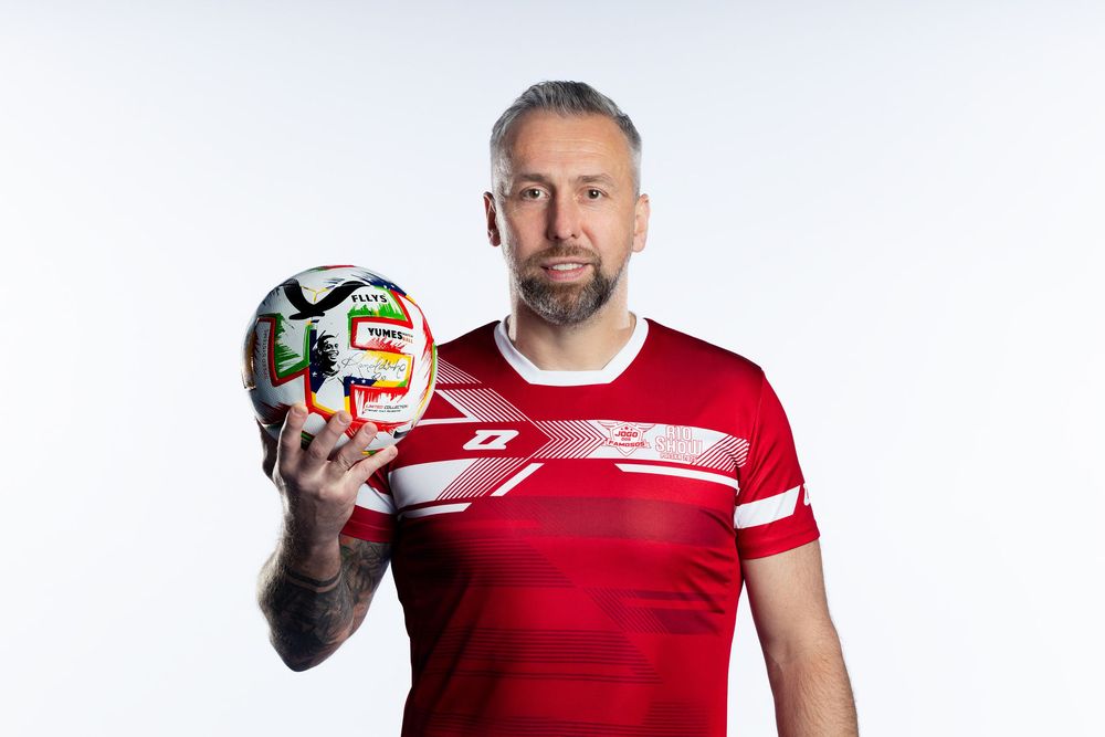 Model sportowy w czerwonej koszulce pozuje z piłką rugby na białym tle. Fotografia biznesowa Lublin.