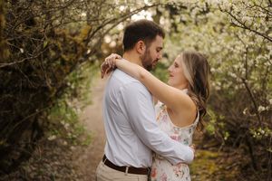 A romantic couple embraces under blooming spring trees during an intimate outdoor photoshoot.