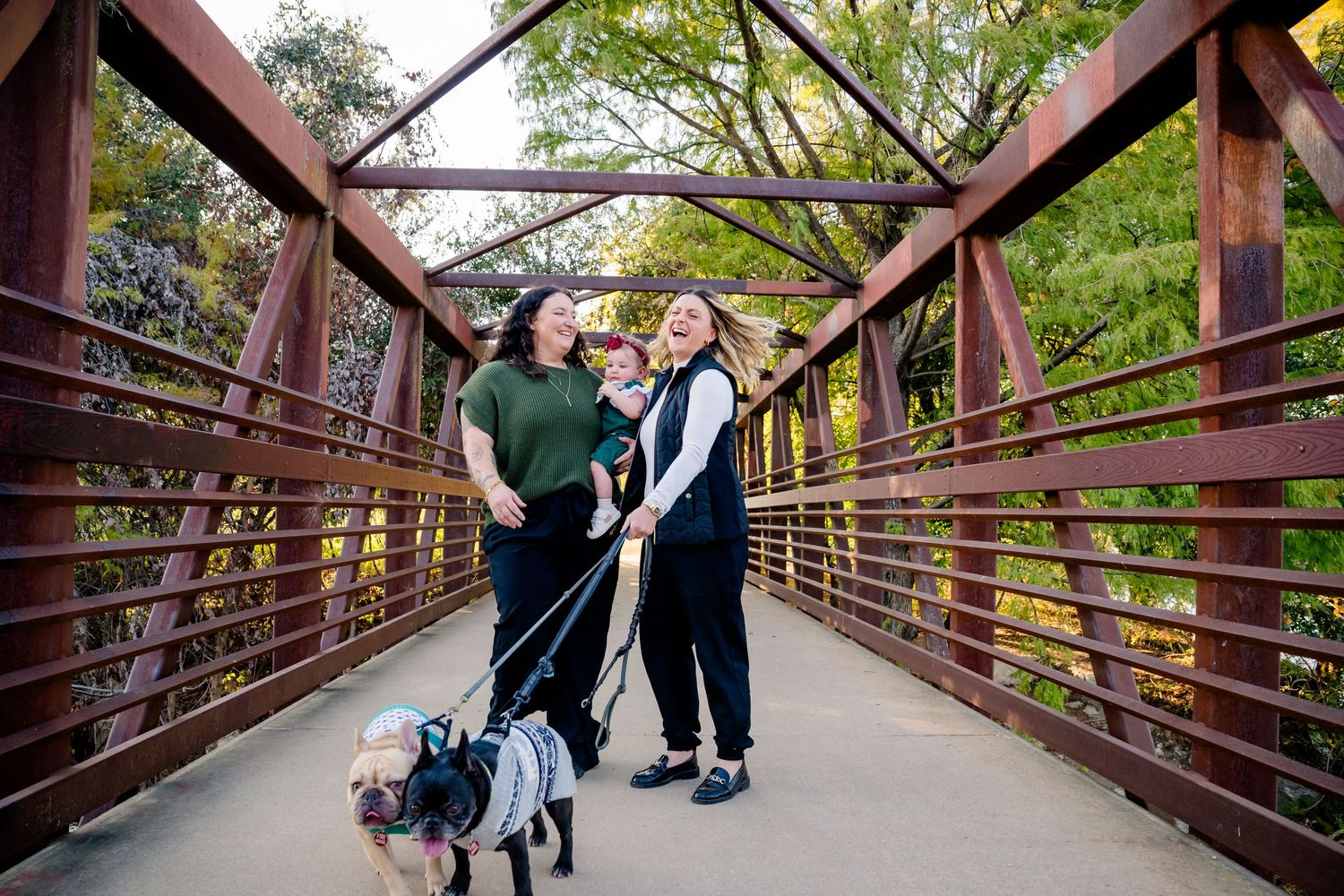 Two people dancing together on a rustic wooden bridge surrounded by green trees and foliage.