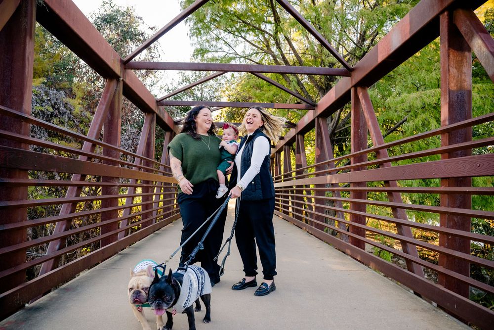 Two people dancing together on a rustic wooden bridge surrounded by green trees and foliage.