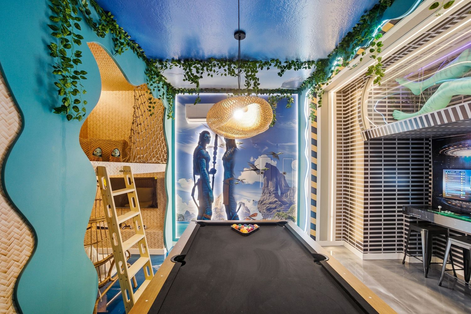A creative office hallway with blue walls, hanging plants, and a silhouette mural illuminated by modern lighting fixtures.