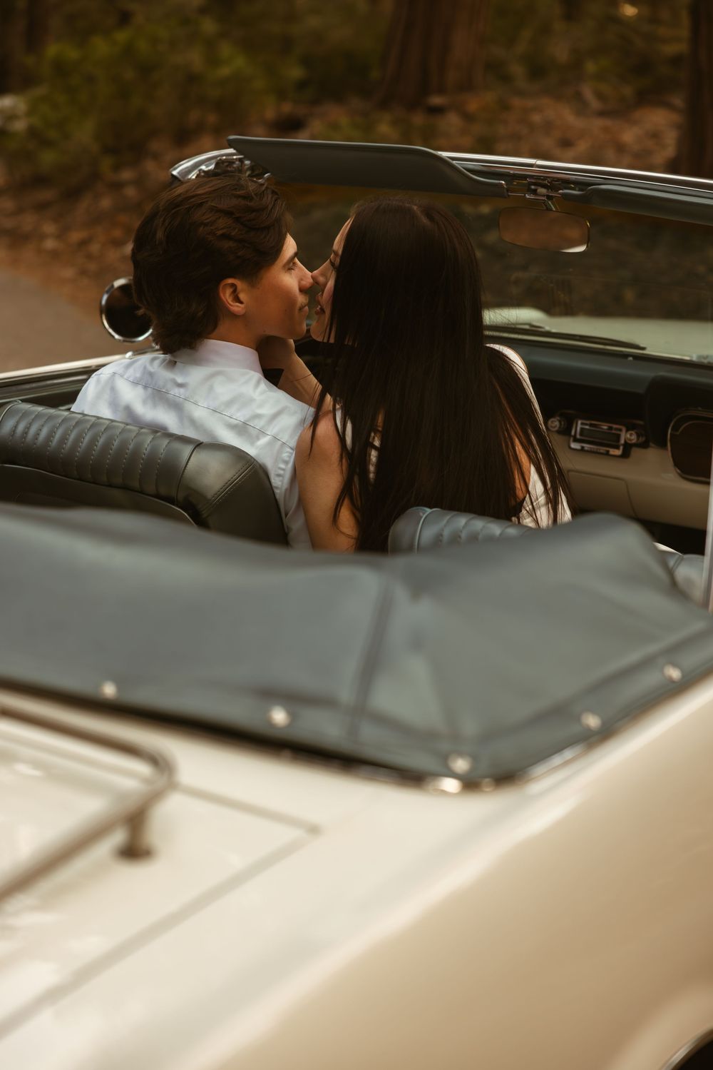 Couple sharing a romantic moment in a vintage car on an autumn day.