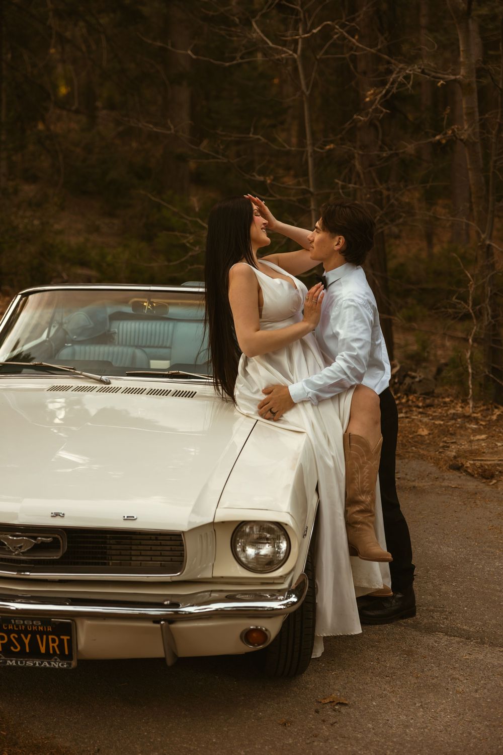 A classic white Ford Thunderbird parked on a wooded road during a romantic photoshoot.