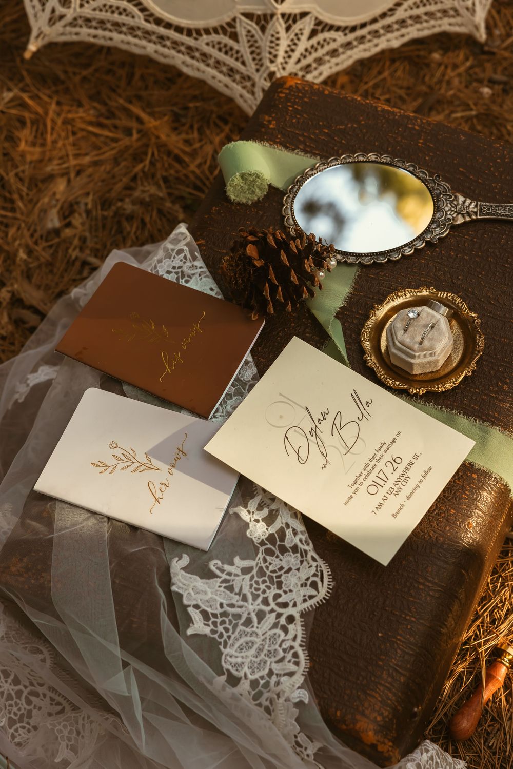 Elegant wedding stationery with white lace doilies and gold calligraphy displayed on dark wooden surface with vintage details.