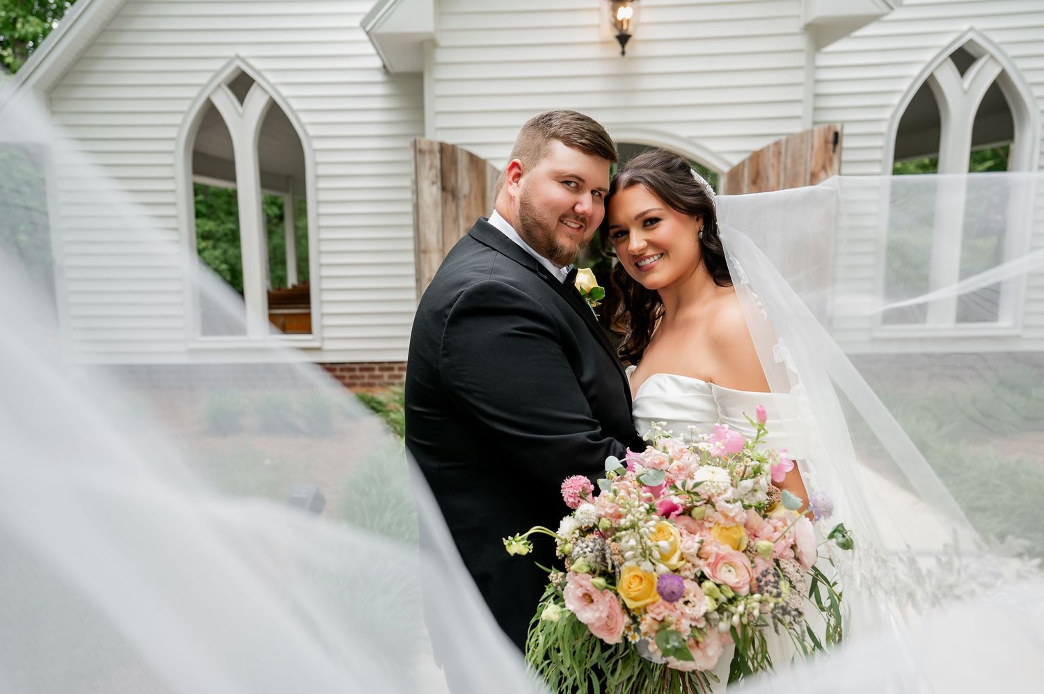 White chapel wedding venue with romantic floral arrangements and veil details.