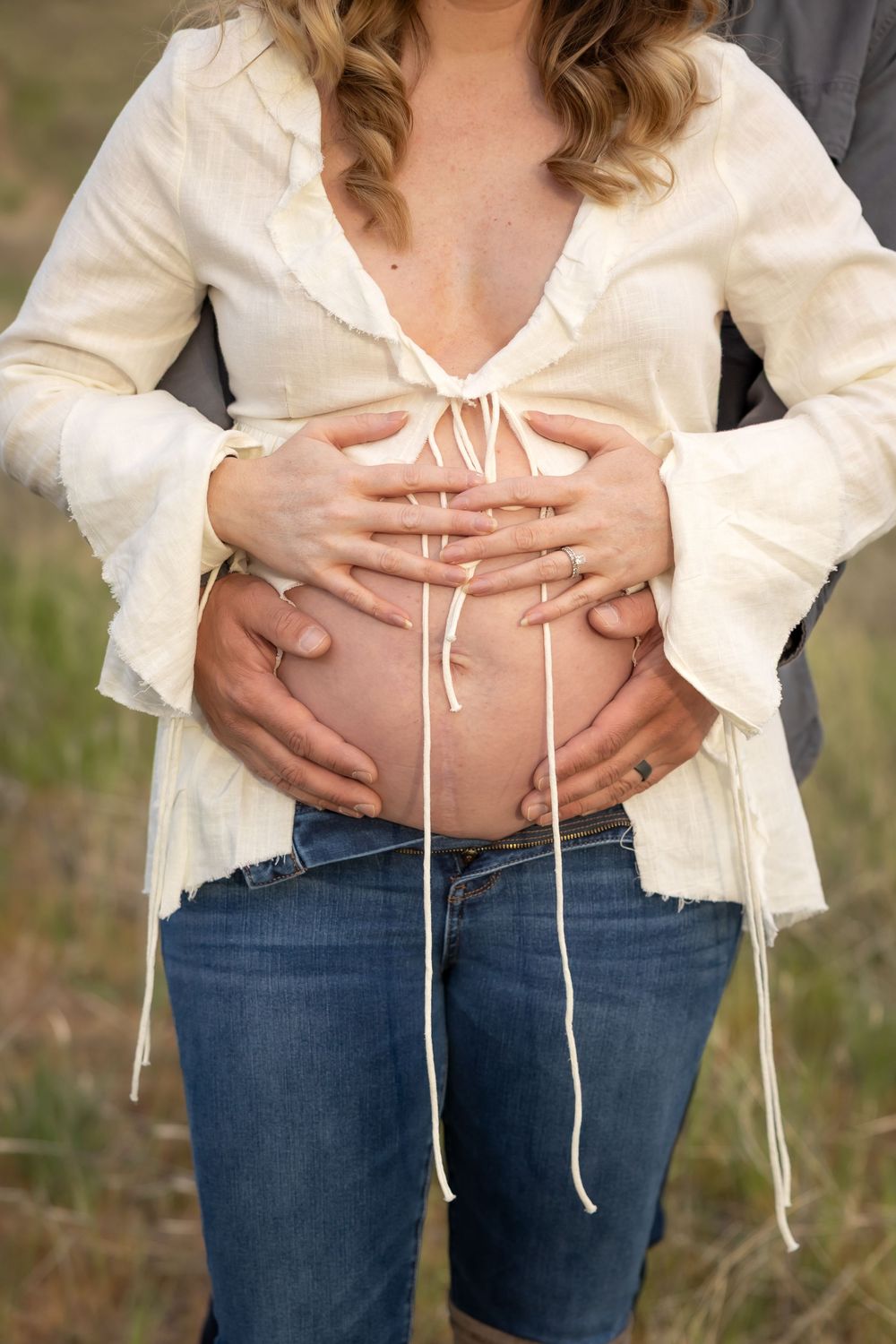 Close-up shots of a pregnant belly in a white lace top and jeans against a natural outdoor backdrop.