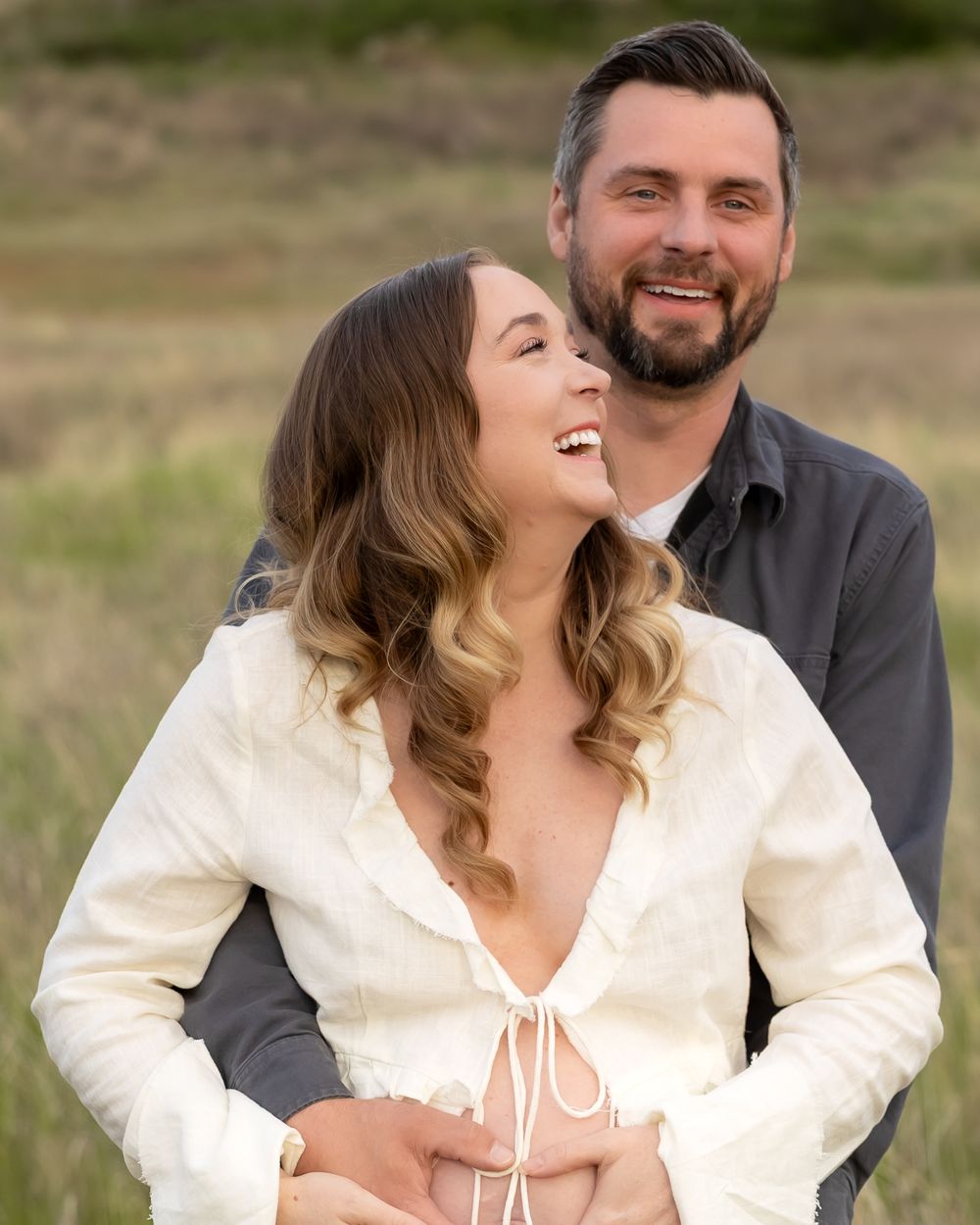 A joyful couple sharing a candid moment together outdoors against a natural landscape.
