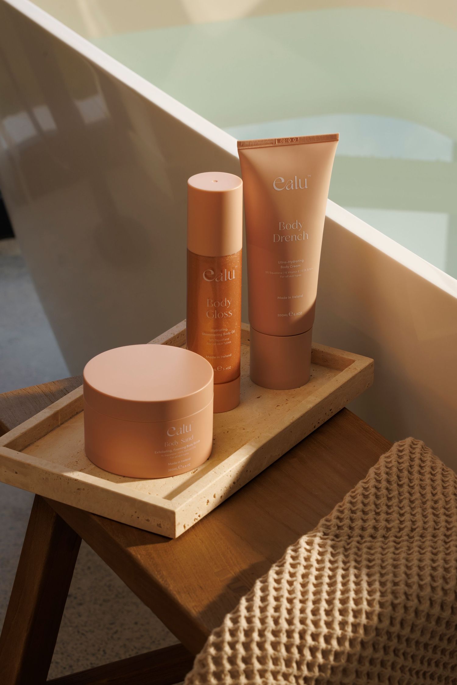 Beauty products in copper-colored packaging arranged on wooden tray.