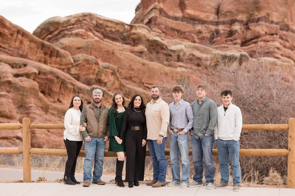 Group photo of people standing together at Red Rocks with dramatic sandstone formations behind them.