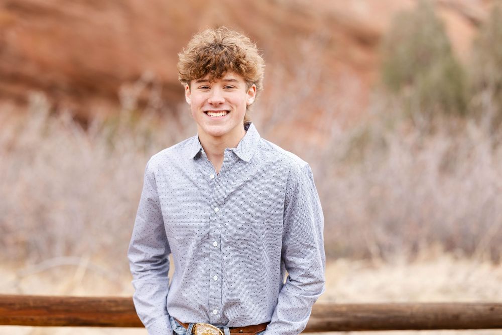 Portrait of person in grey button-up shirt against natural desert setting.