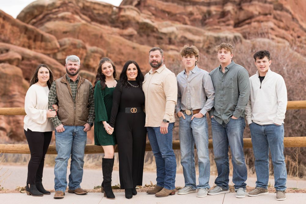 A group poses in front of dramatic red rock formations in an outdoor desert setting.