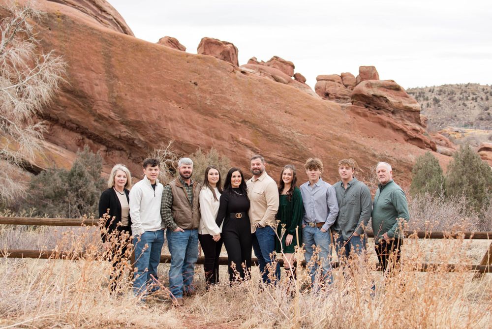 Family group photo with scenic red rock formations and brush in the background.