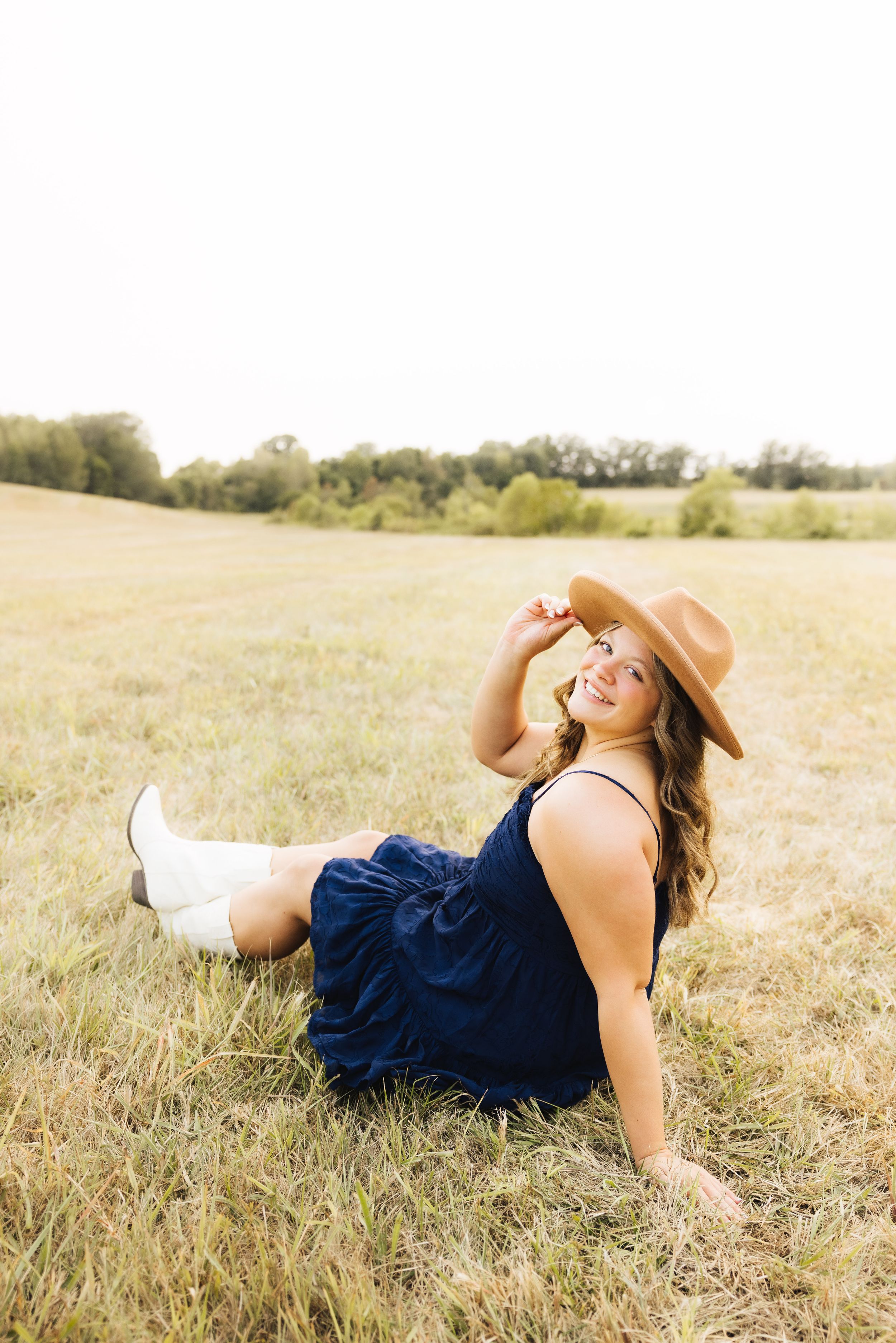 Artistic senior portrait series in a golden field during sunset.