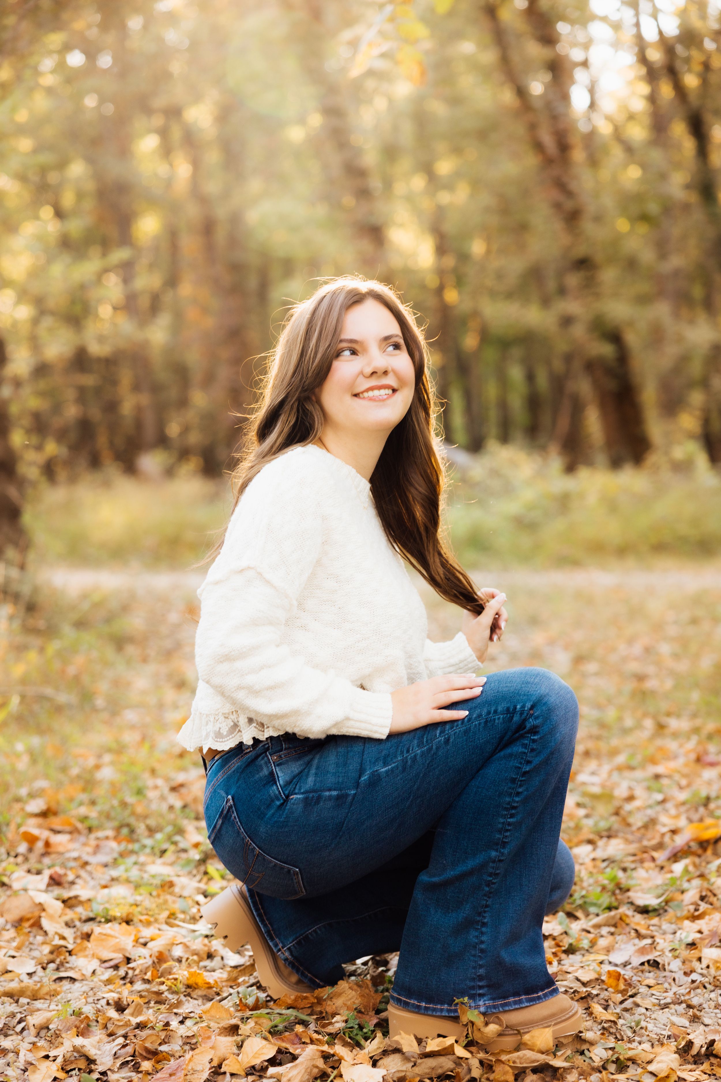 Autumn senior outdoor photoshoot with fallen leaves and natural lighting.