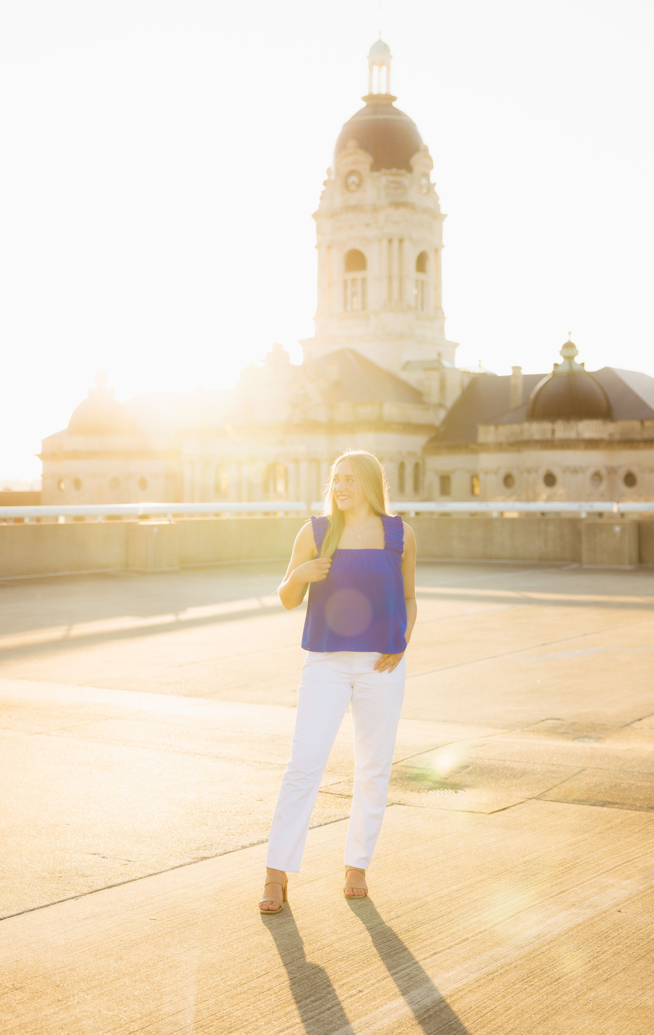 Senior stands in front of a domed building during golden hour sunset.