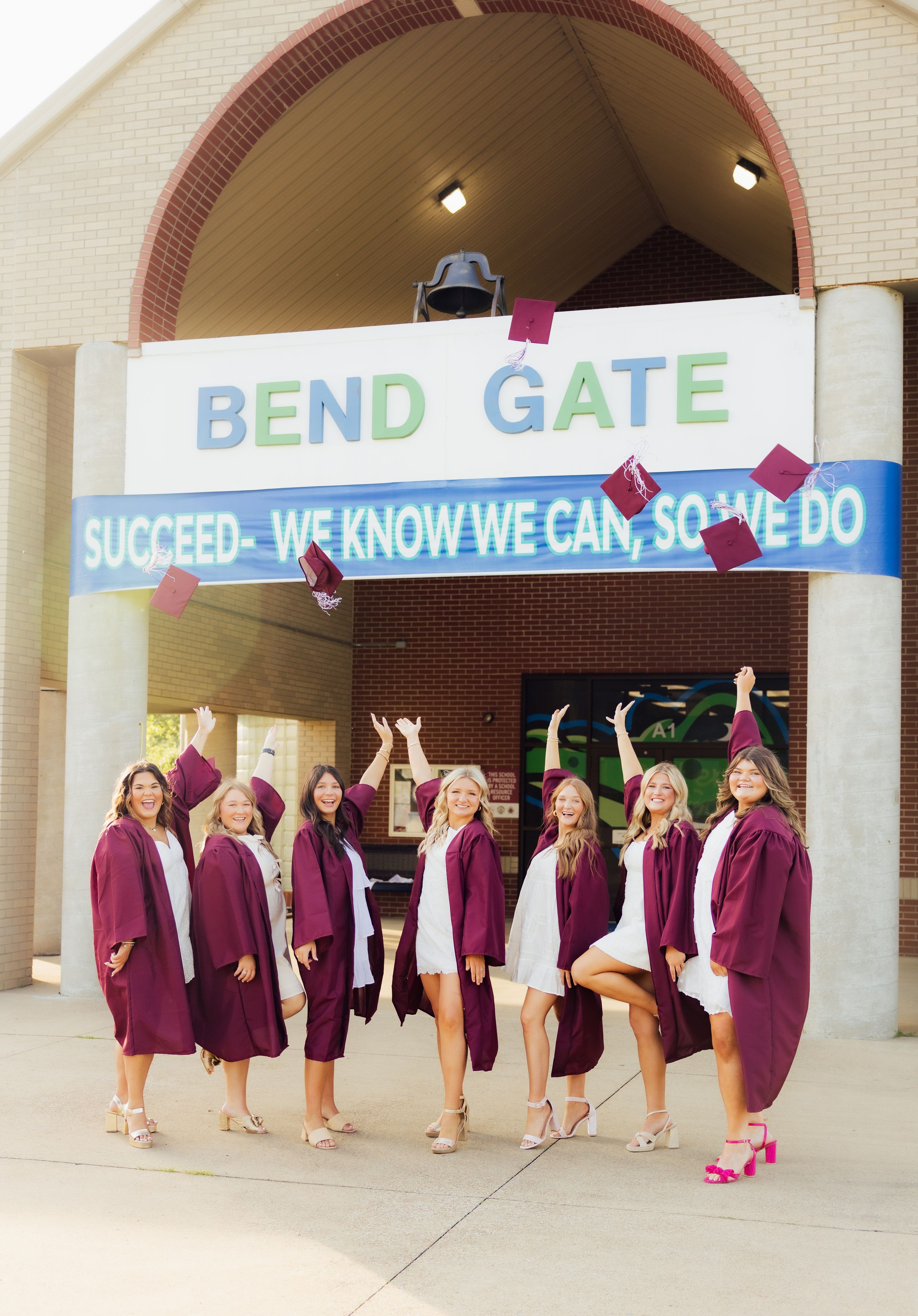 Group photo senior session at Bend Gate with inspirational signage and matching burgundy outfits.