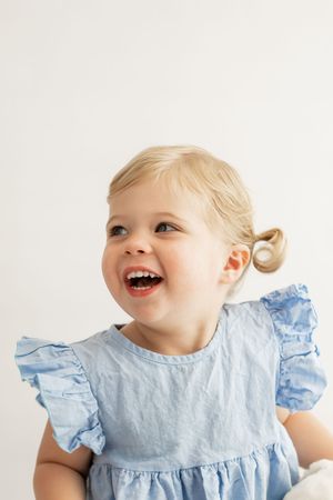 A series of four close-up photos showing joyful expressions and light blue ruffled clothing against a white background.