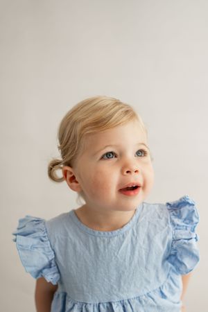 Four sequential photos showing a toddler in a light blue ruffle sleeve dress looking upward with delight.