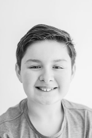 Black and white portrait of a young person with short hair wearing a gray t-shirt smiling at the camera.