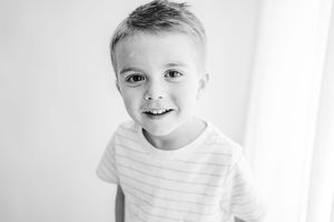Portrait of a child in a striped t-shirt smiling against white background.