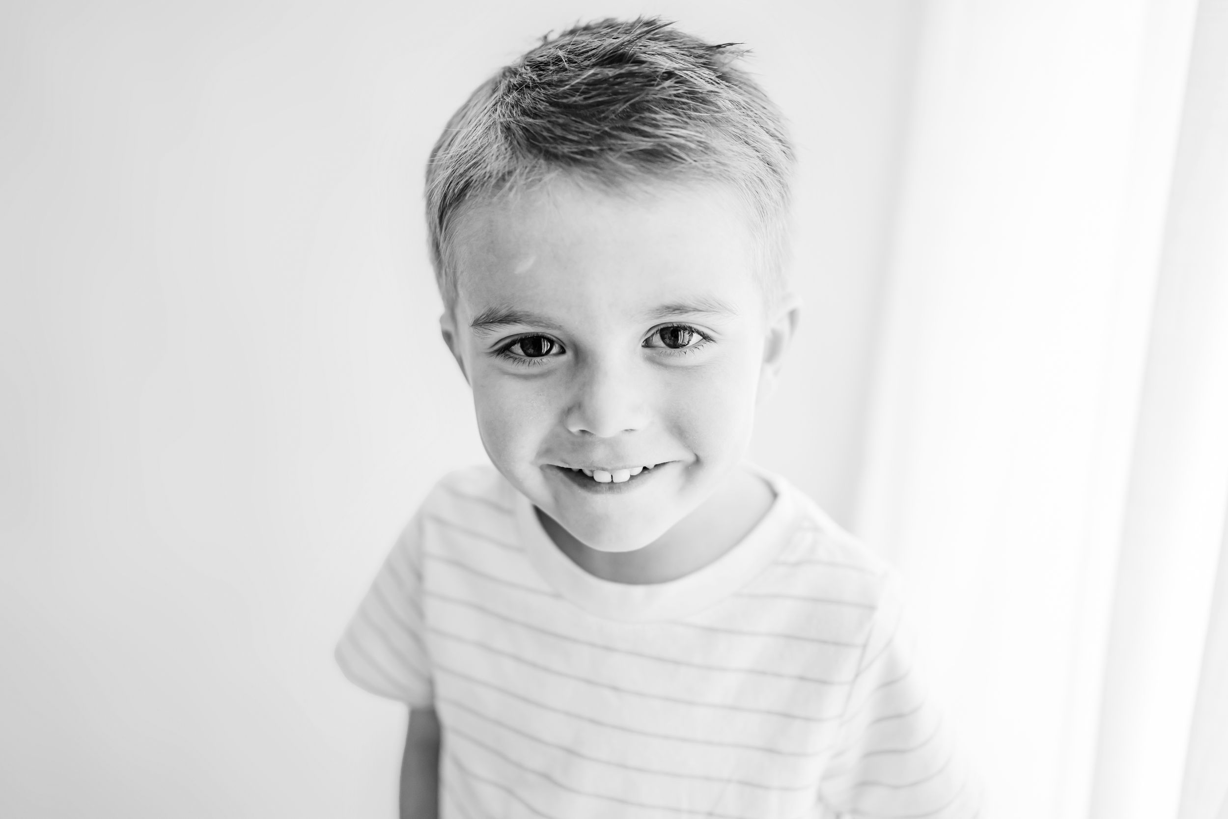 Black and white close up portrait of child wearing striped shirt.