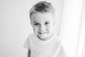 Black and white close up portrait of child wearing striped shirt.