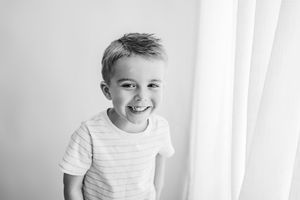 Joyful child in striped shirt laughing in black and white photo.