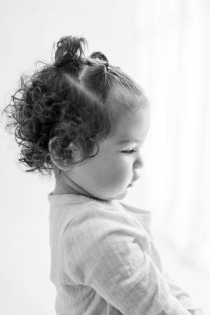 Black and white portrait series showing close up views of a toddler with curly hair looking different directions.