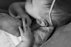 Black and white close-up of sleeping child's hand and face.