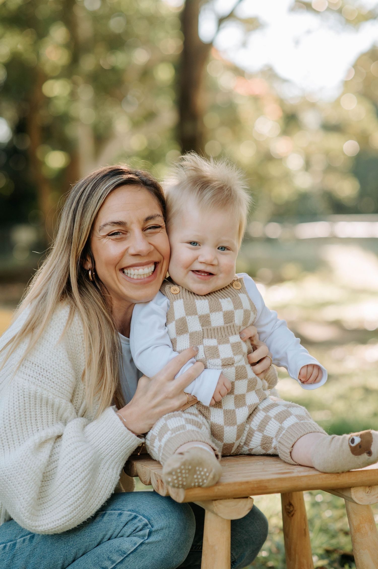 Happy moment captured between parent and baby sitting on wooden stool outdoors.