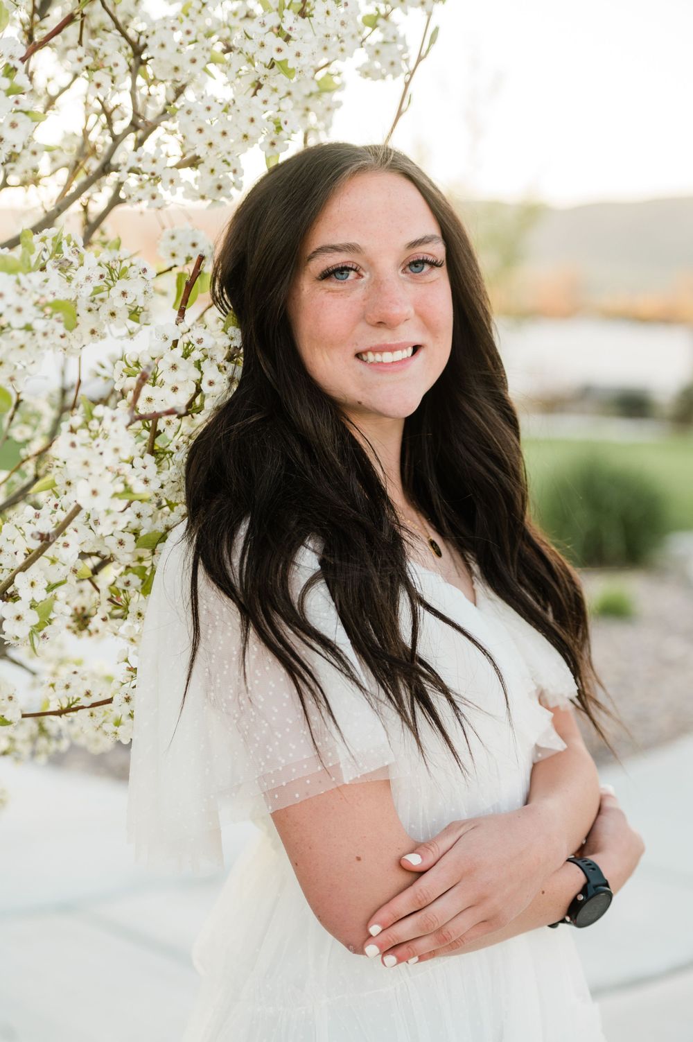 Portrait in front of blooming white spring blossoms wearing white dress.