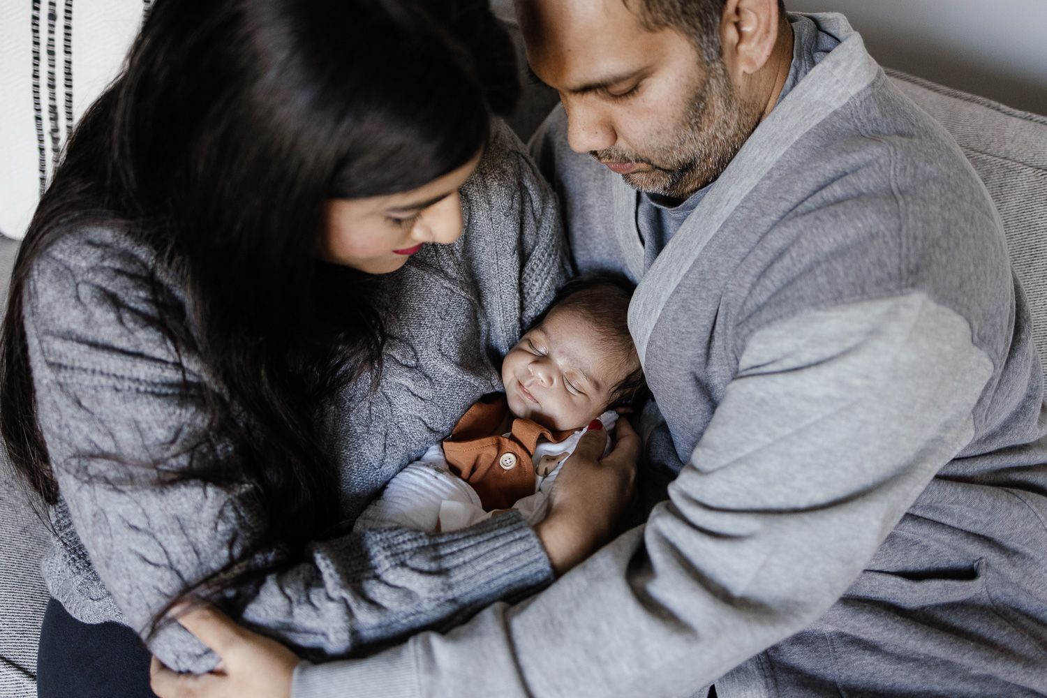 Family cuddles sleeping baby during their baby photo session in San Jose