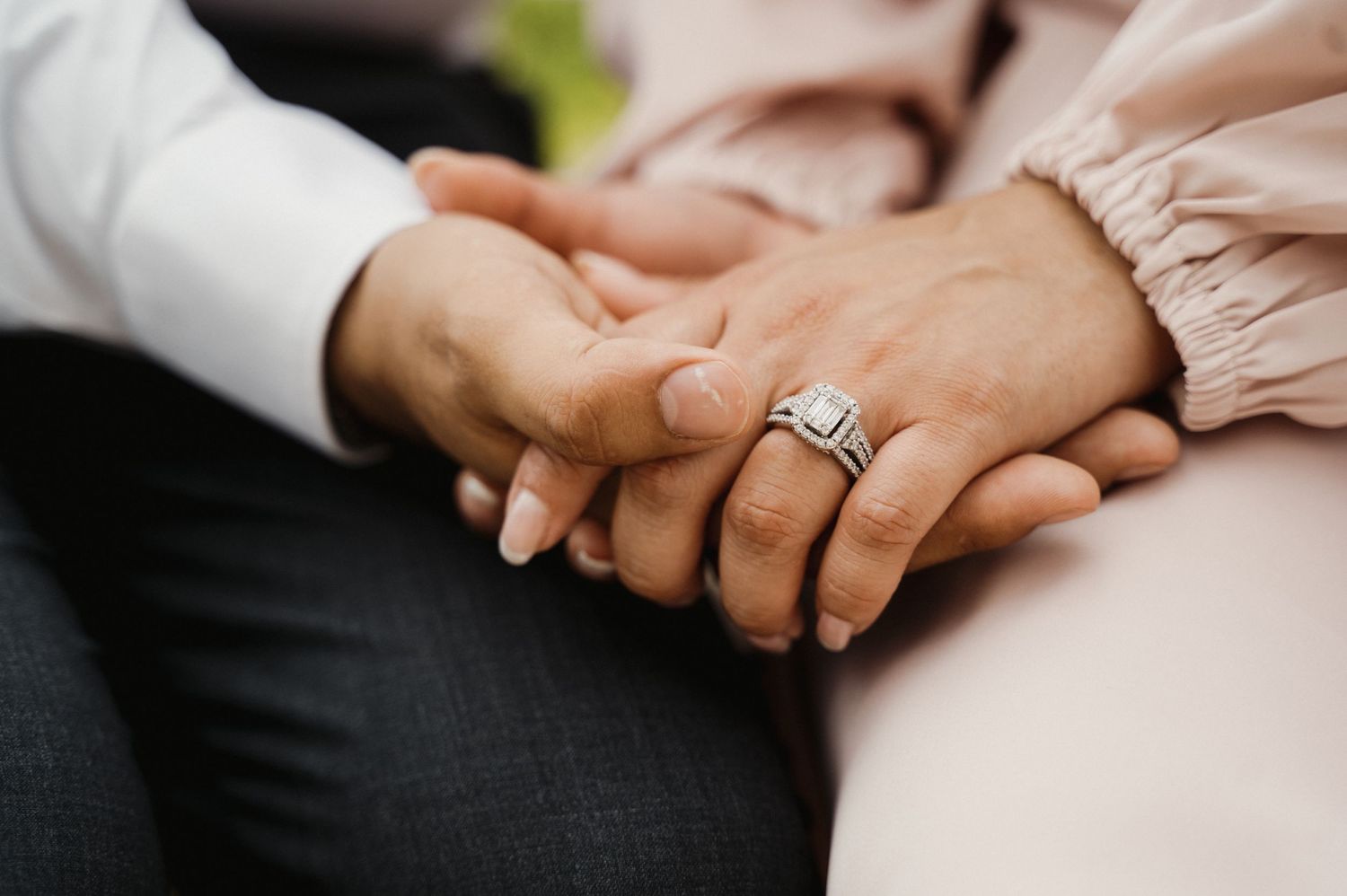 Close-up shot of hands with engagement ring showing tender moment between couple.