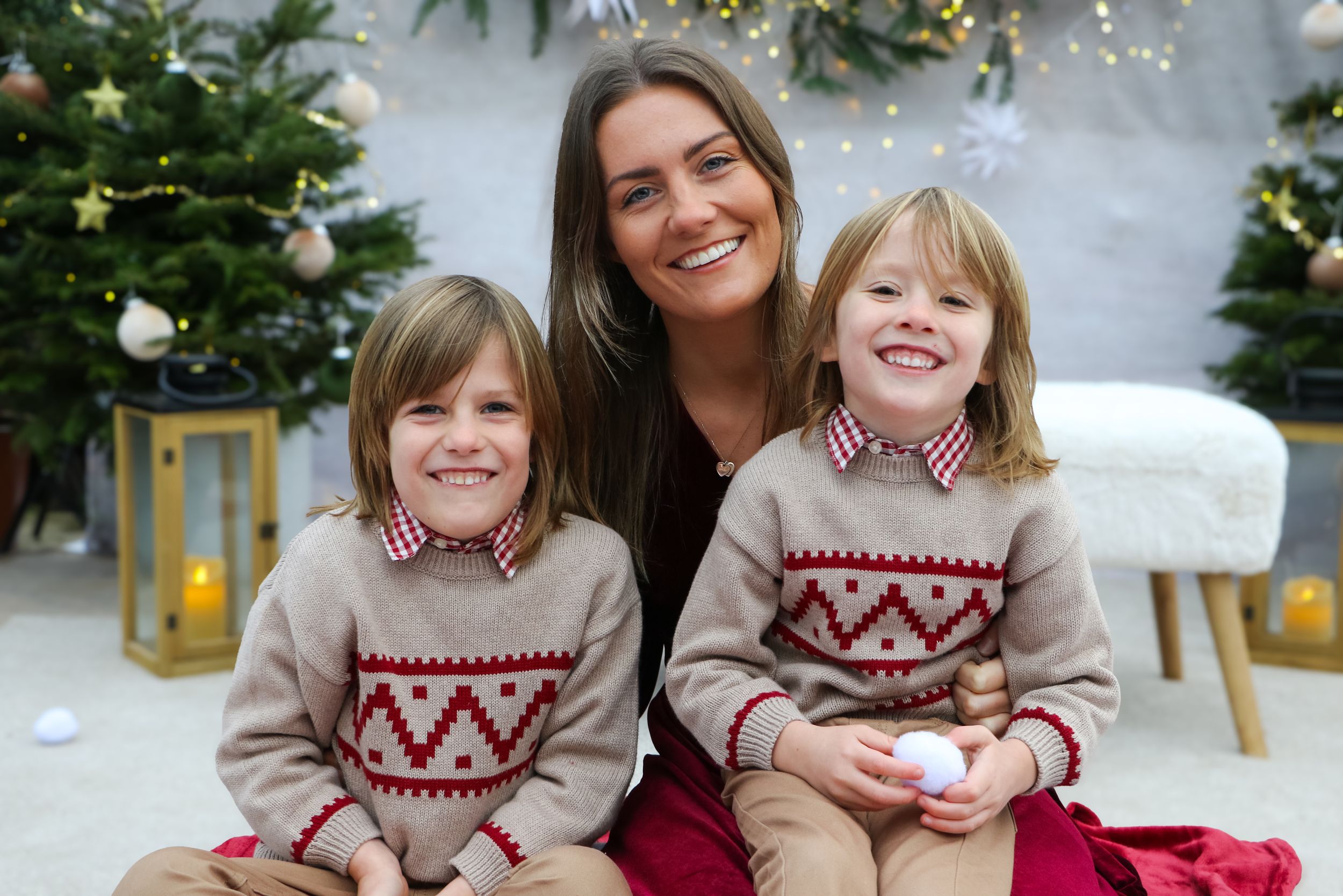 Happy group in coordinated holiday outfits poses together by decorated Christmas tree.
