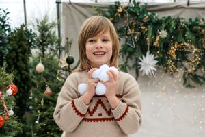 Festive holiday scene with beige patterned sweater against Christmas decorations and twinkling lights.