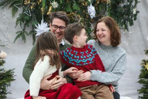 Family of four enjoying holiday portrait session with Christmas decorations.
