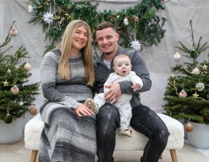 Festive family portrait with decorated Christmas trees and white winter decor.