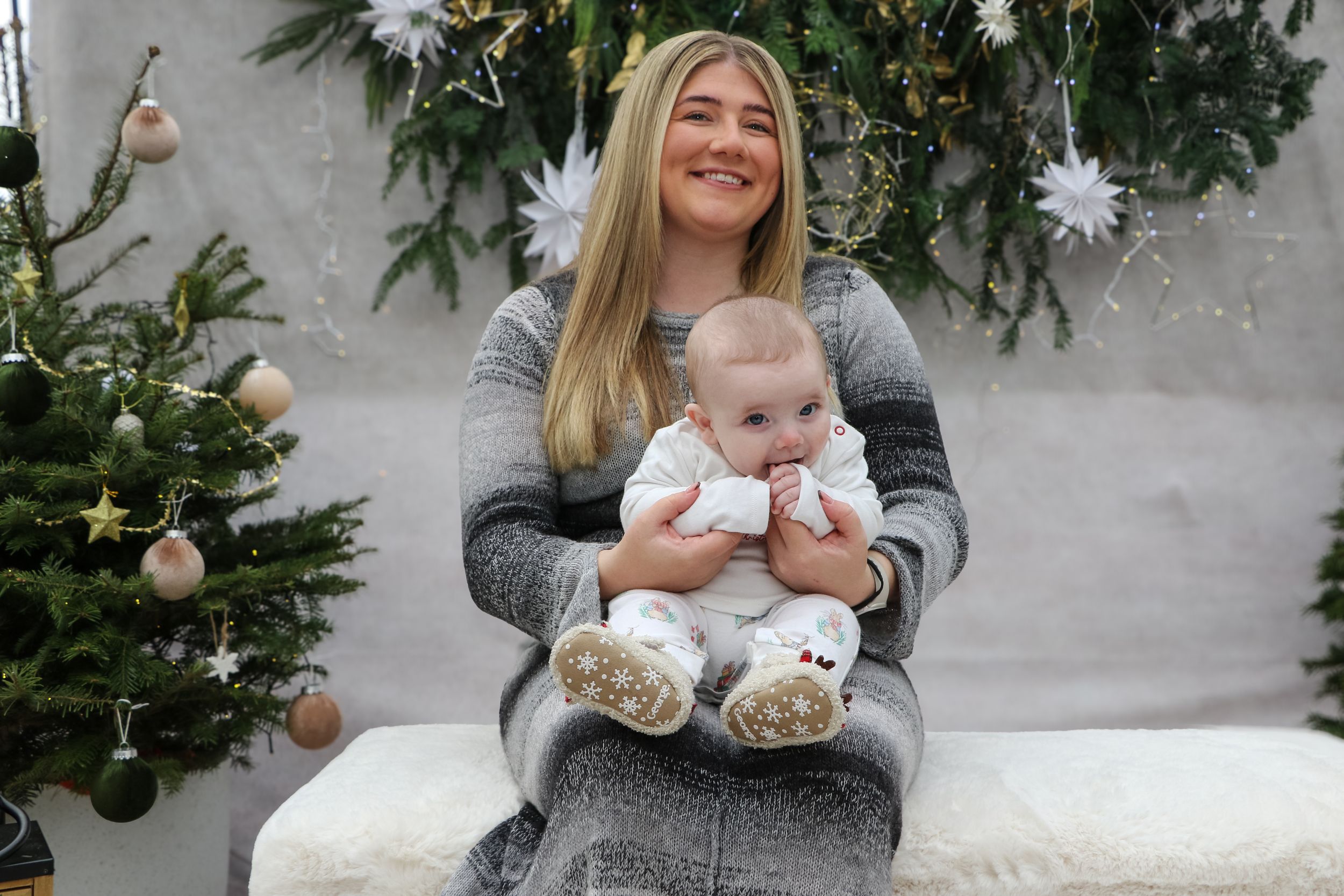 Family holiday portrait with Christmas decorations and pine branches in background.