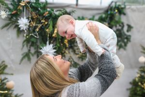 Joyful moment between parent and child during holiday photoshoot with Christmas decorations.