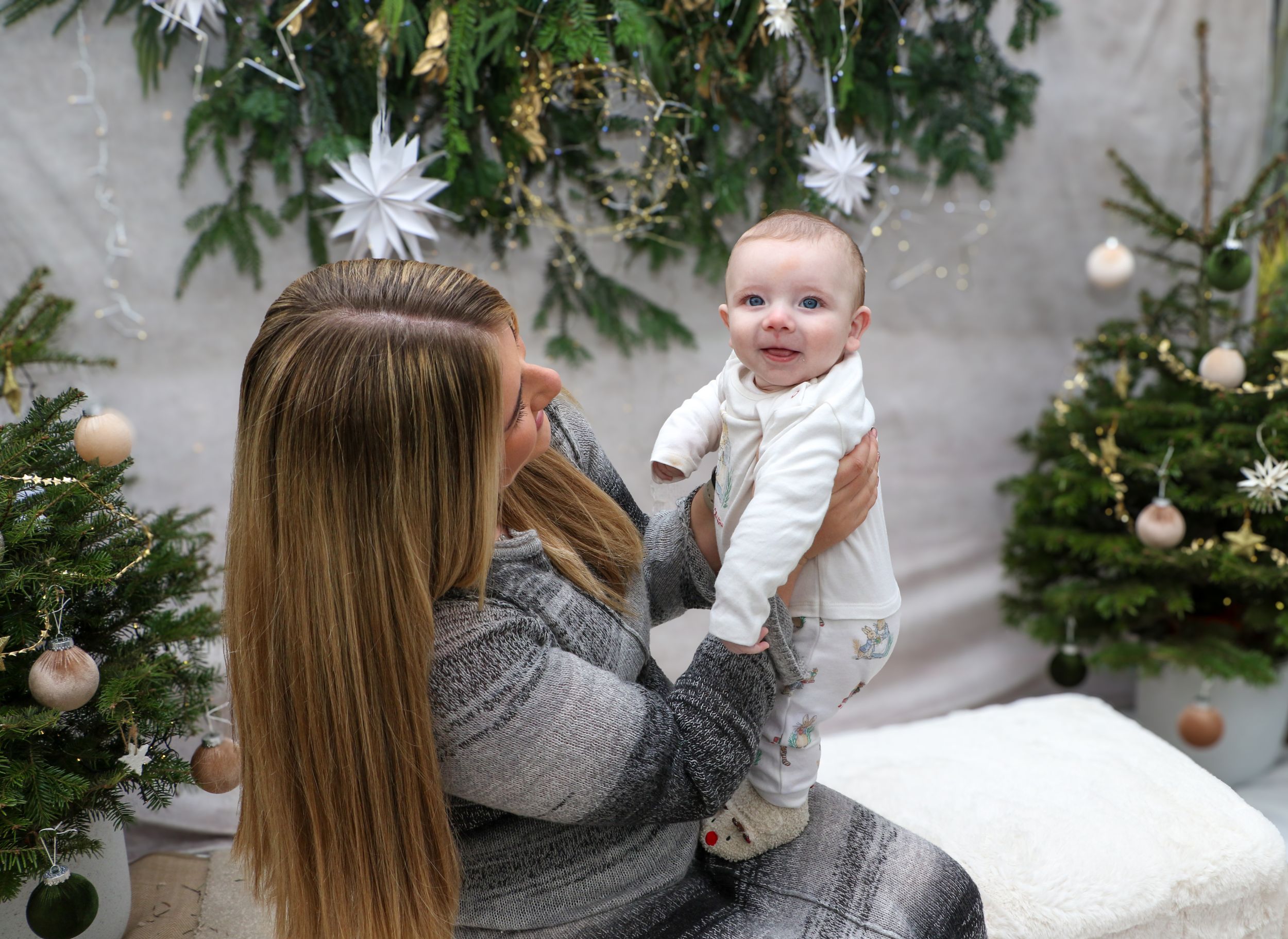 Holiday portrait with Christmas trees and decorative white stars in background.