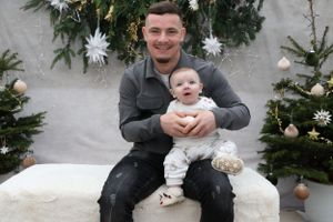 Holiday portrait against Christmas tree backdrop with white star decorations.
